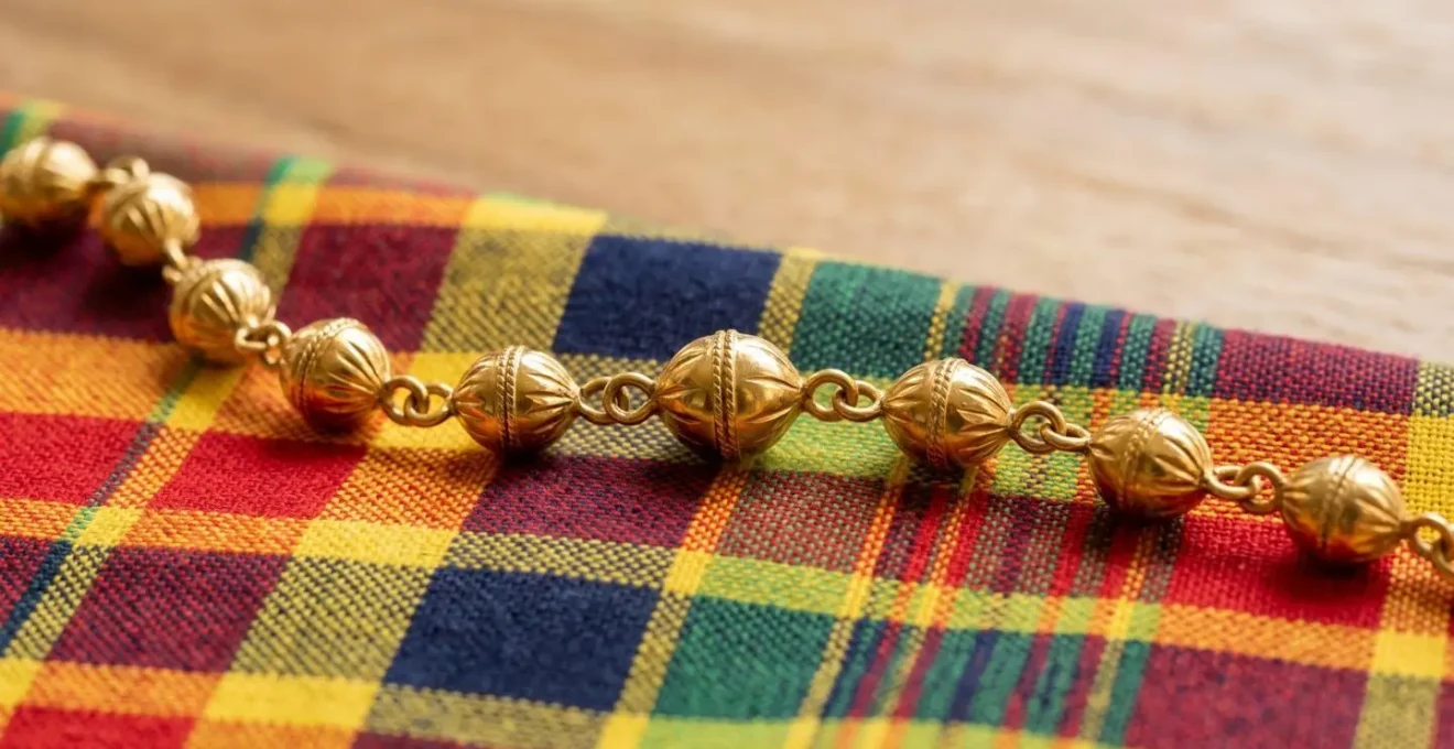 Collier avec grains d'or antillais en or jaune posé sur tissu madras traditionnel aux motifs géométriques colorés
